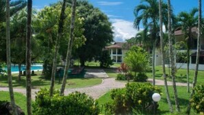 Een tropisch resort met een zwembad, palmbomen en een verzorgde tuin.