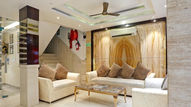 A modern living room with two sofas, a coffee table, and a ceiling fan. - TG Tashkent Hotel (New Delhi)