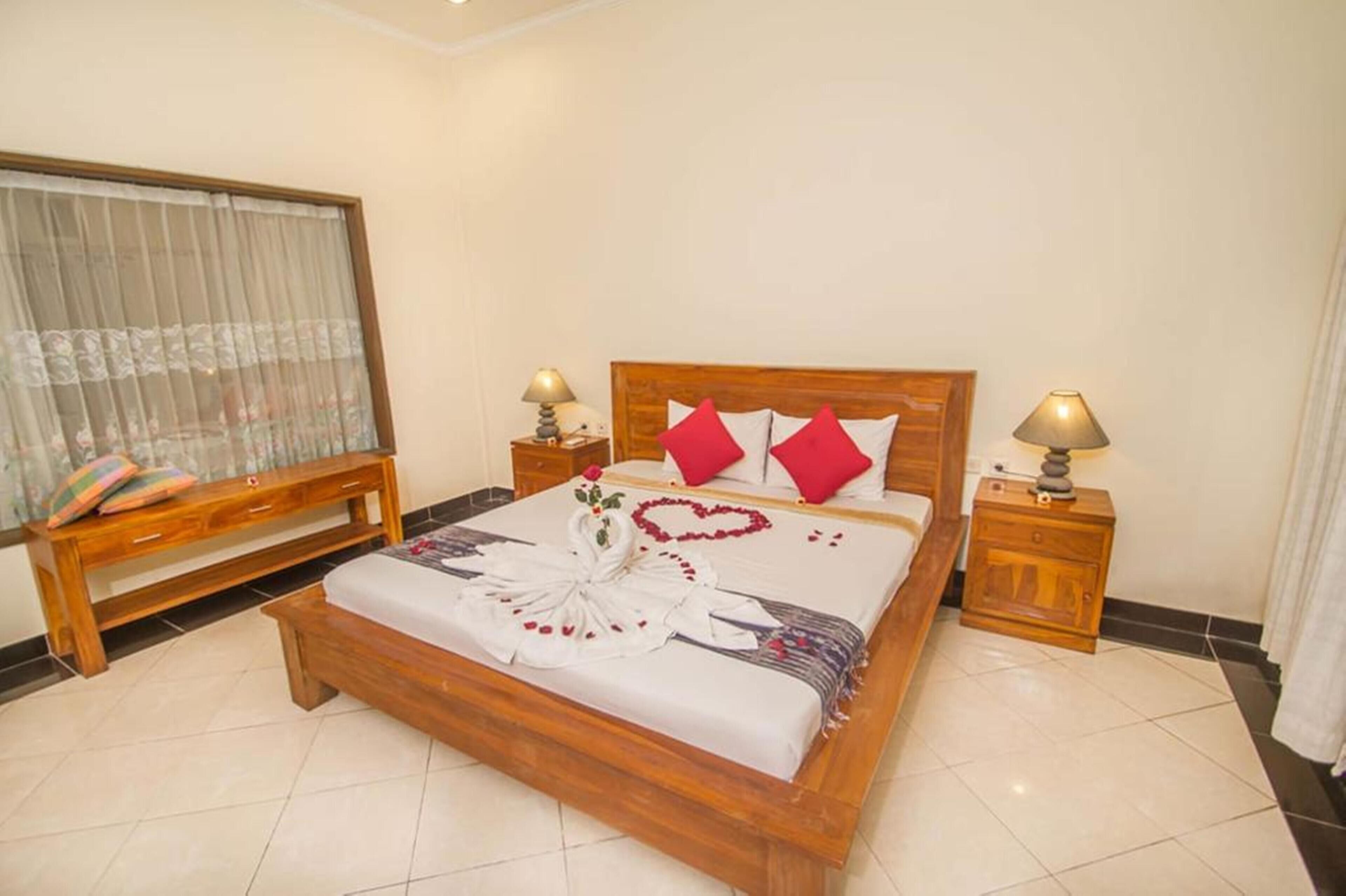 A neatly arranged bedroom with a wooden bed, a bench, and two bedside tables with lamps.
