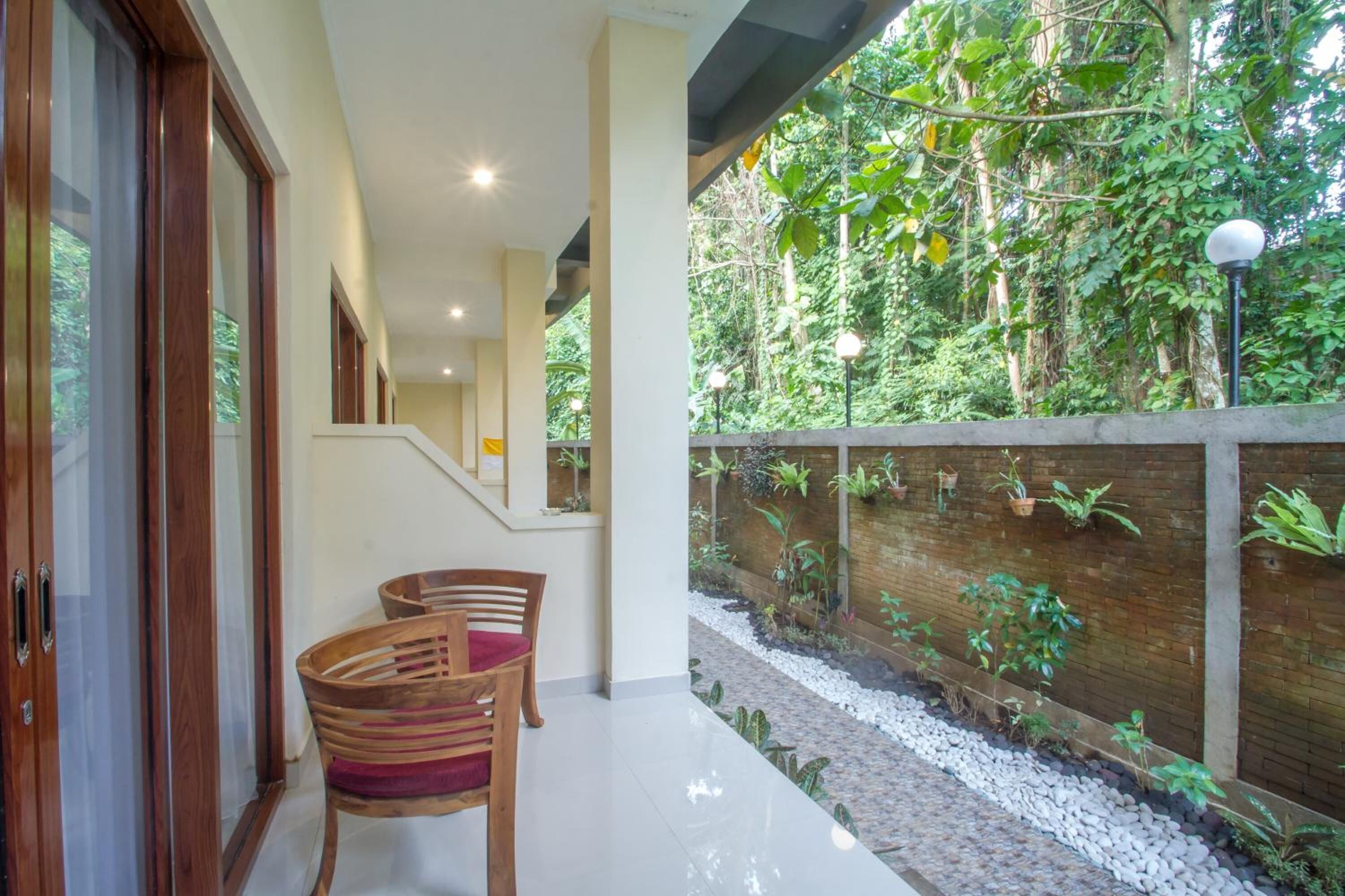 A modern interior with a staircase leading to a balcony, a wooden bench, and a wall with potted plants.