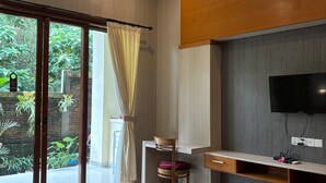 A modern bedroom with a large bed, a desk, and a TV. - Adi Jaya Cottages Jungle Suites by EPS (Ubud)
