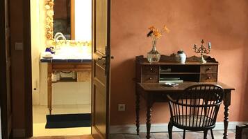 A room with a wooden desk, a chair, a mirror, and a rug.
