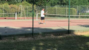 Un terrain de tennis avec un filet, une échelle et une clôture.