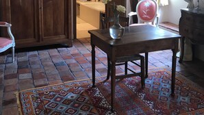 Una habitación acogedora con un armario de madera, una mesa con un florero, una alfombra estampada y una silla.