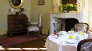 Una habitación con chimenea, una mesa de comedor lista para el desayuno y un espejo arriba.