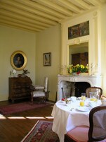 Una habitación con chimenea, una mesa de comedor lista para el desayuno y un espejo arriba.