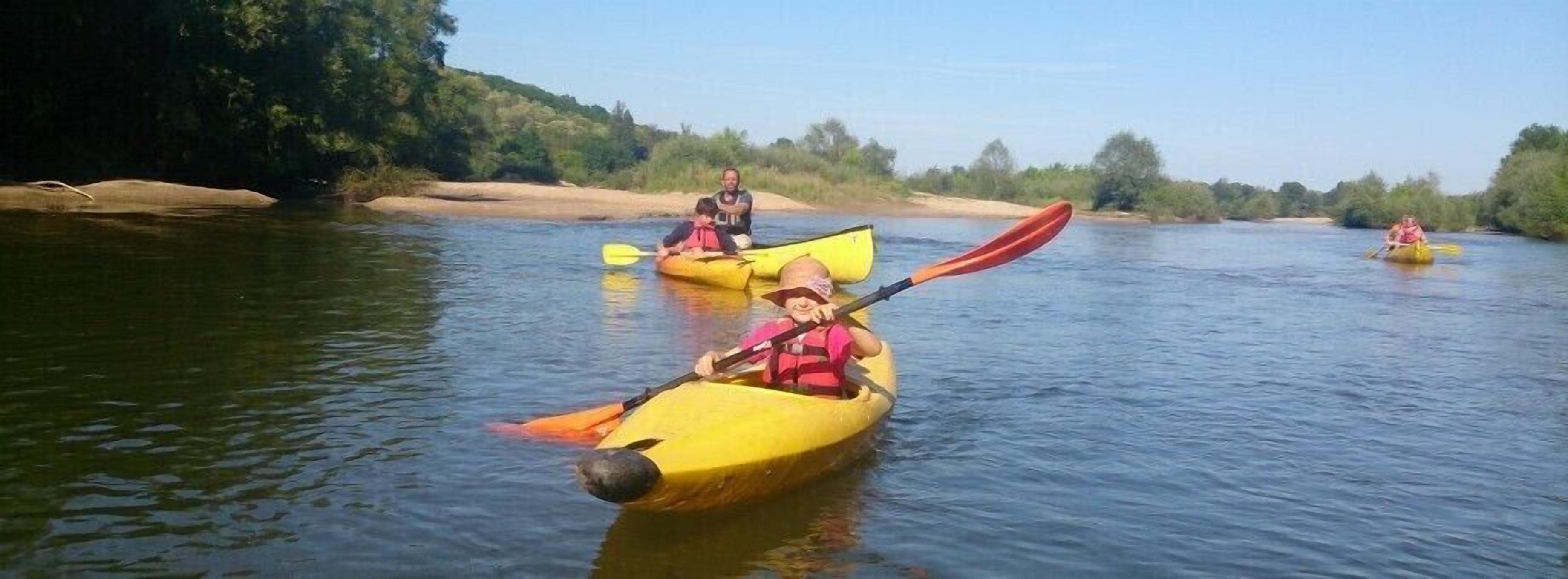 Personas haciendo kayak en un río tranquilo rodeado de vegetación.