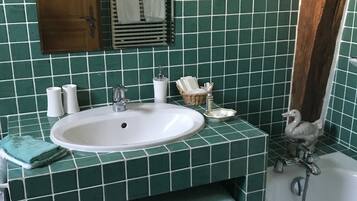 Un baño con un lavamanos blanco, azulejos verdes, una puerta de madera, un espejo y una zona de ducha.