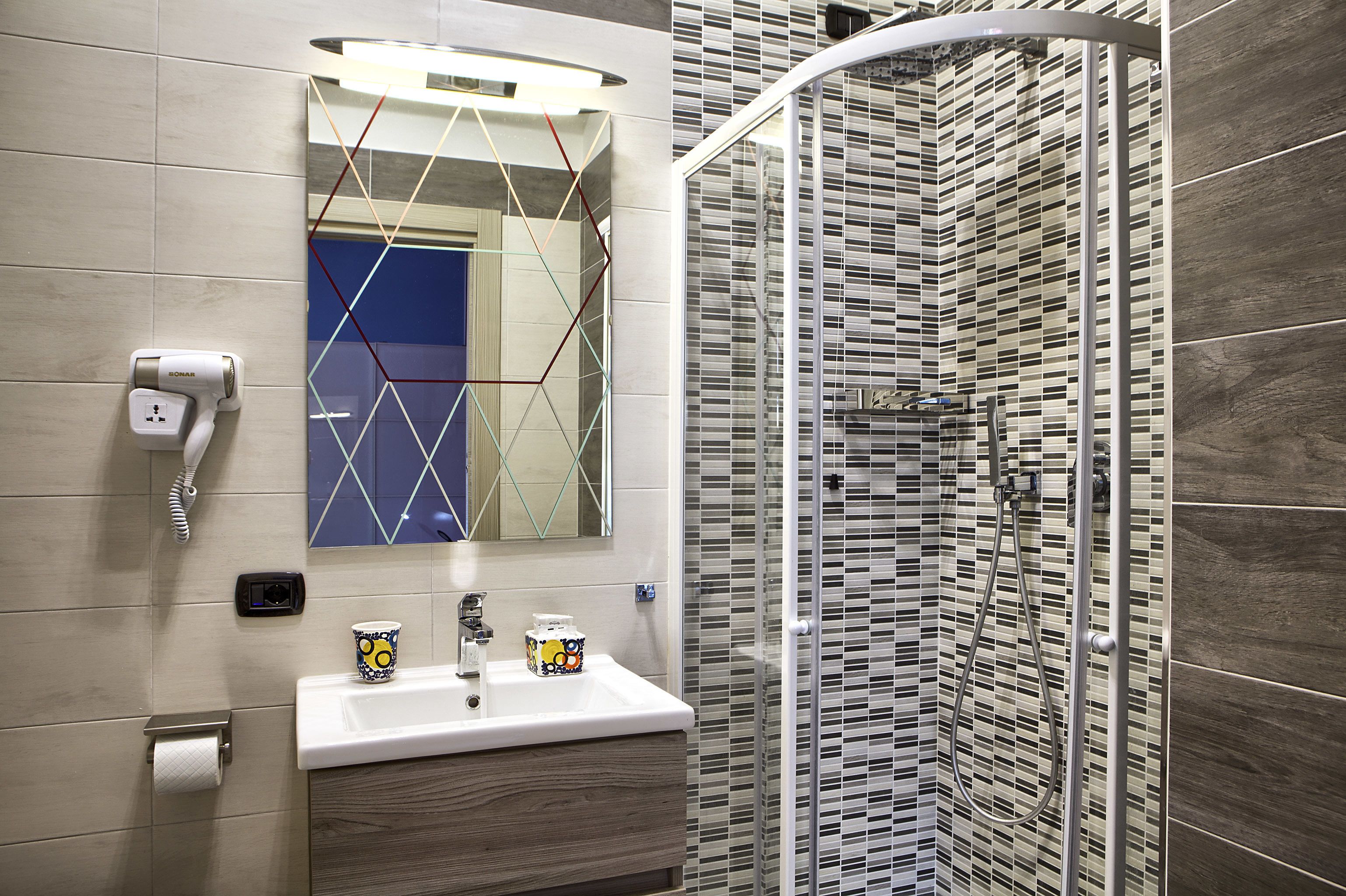 Ein modernes Badezimmer mit Waschbecken, Spiegel und Dusche.