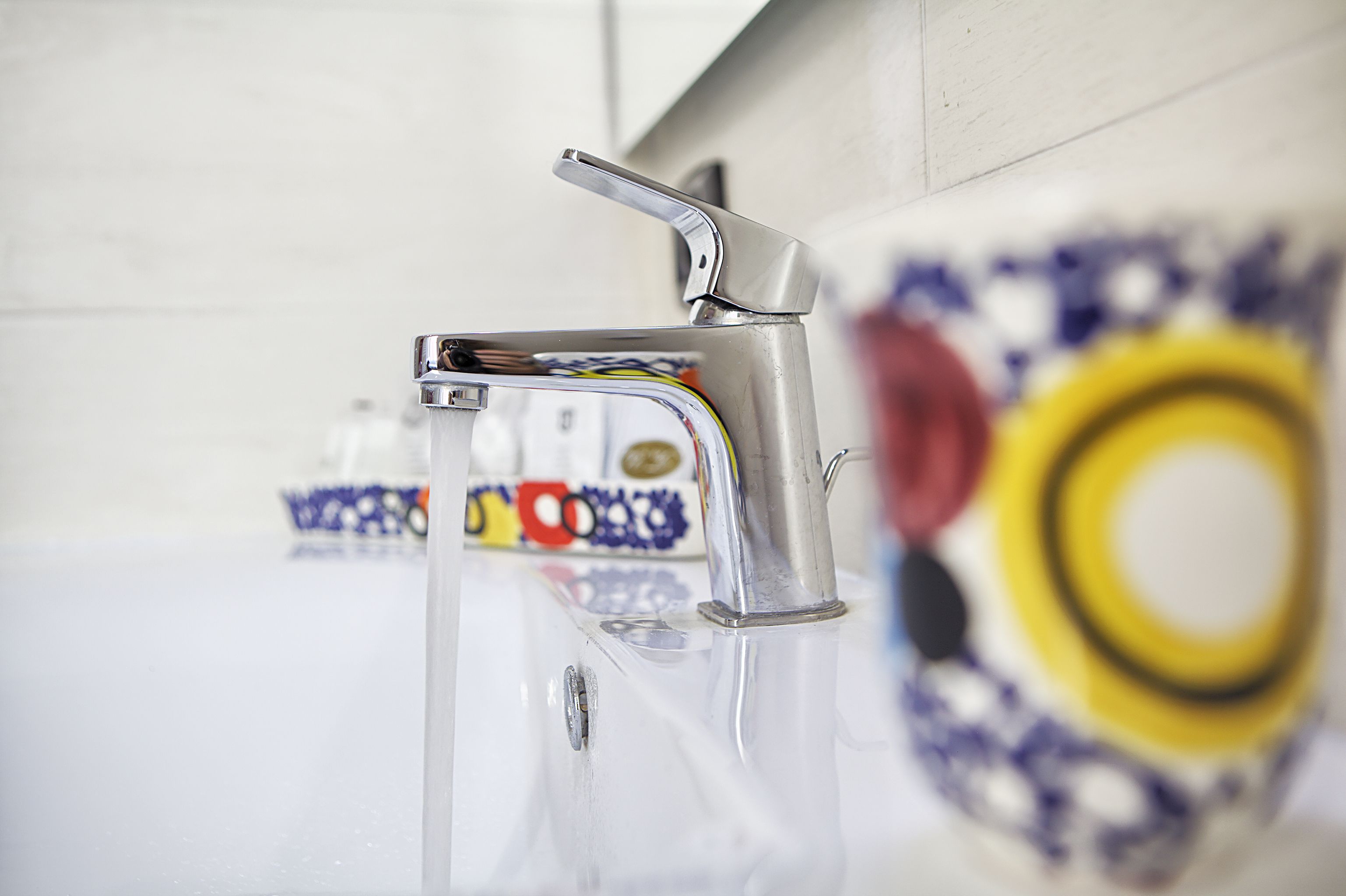A bathroom with a modern faucet and a decorative tile backsplash.