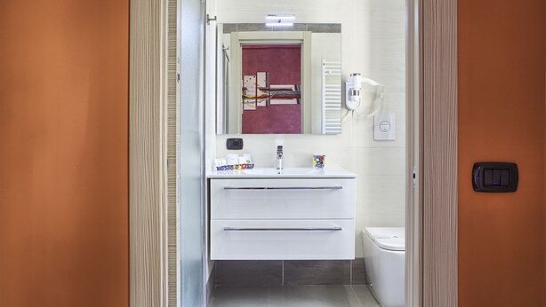 Une salle de bain moderne avec un meuble-lavabo blanc, un miroir, un porte-serviettes et des toilettes.