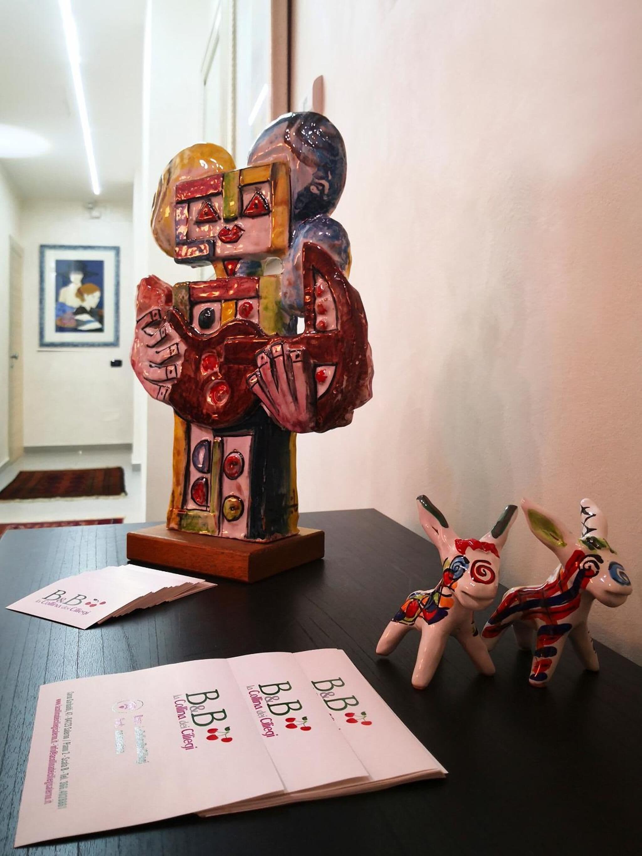 Uma mesa com uma escultura em cerâmica, duas figuras de animais em cerâmica e um folheto.