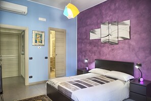 Een slaapkamer met een bed, nachtkastjes, een spiegel aan de muur en een deur.