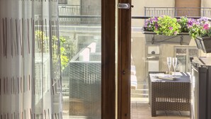 A balcony with wicker furniture, a hanging planter with flowers, and a glass door leading to the interior. - La Collina dei Ciliegi (Salerno)