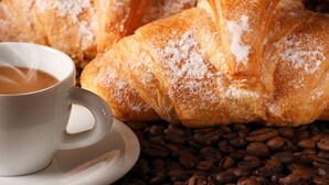 A cup of coffee and a croissant on a table with coffee beans. - La Collina dei Ciliegi (Salerno)