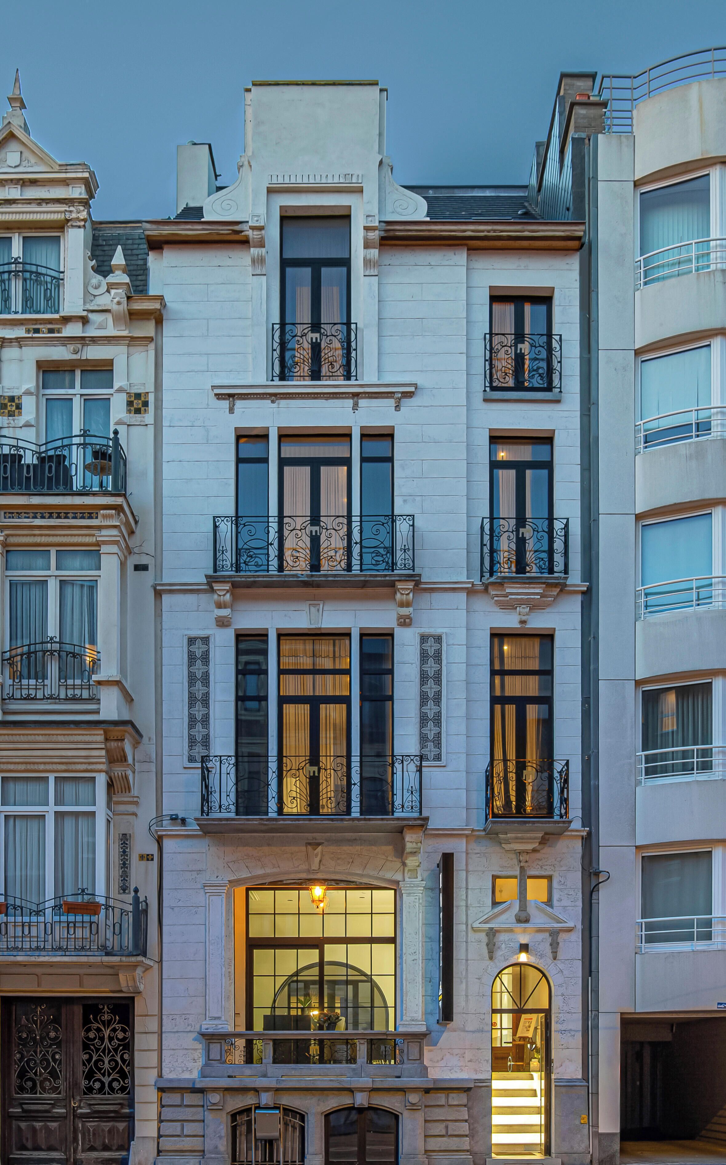 Een meerlaags gebouw met balkons, grote ramen en een klassieke architectuur.