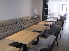 Un comedor moderno con un banco largo y acolchado, además de varias mesas y sillas.