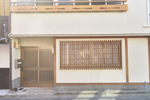 A traditional Japanese building with a wooden gate, a sliding door, and a window with vertical bars. - Kanki-No-Yado-Nishijin (Kyoto)