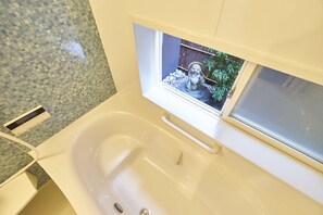 A bathroom with a bathtub, a window, and a tiled wall. - Kanki-No-Yado-Nishijin (Kyoto)