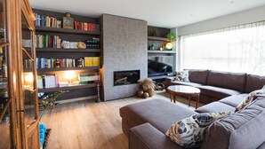 A modern living room with a fireplace, a large bookshelf, a sofa, and a television. - Sable d'O (Ostend)