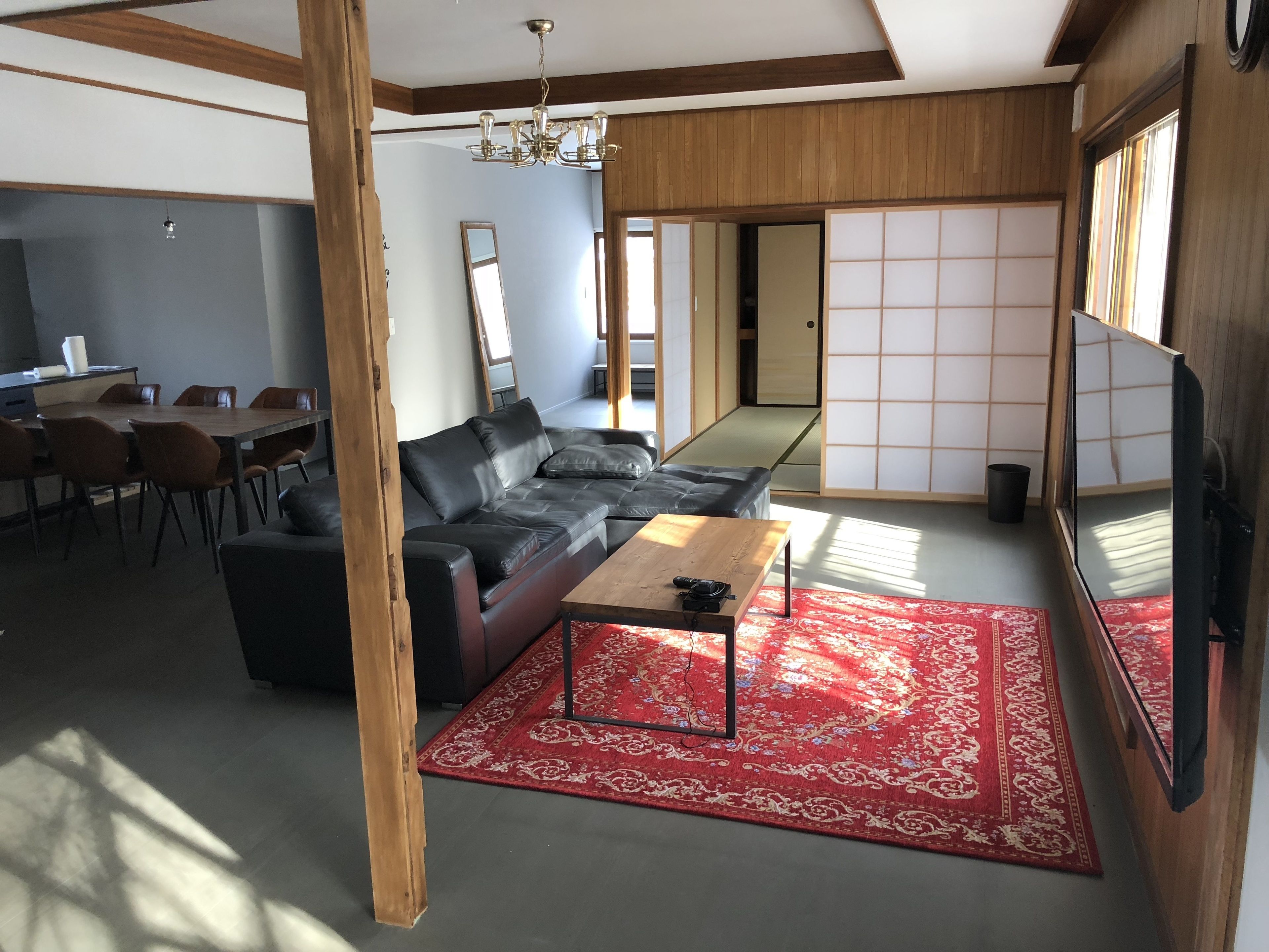 A modern living room with a sectional sofa, a wooden coffee table, and a red patterned rug.