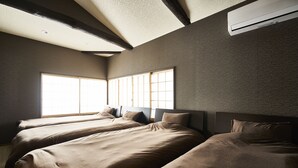 Een kamer met drie bedden, een groot raam en een airconditioning.