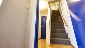 Una scala con corrimano, una porta in cima e un interruttore sulla parete.