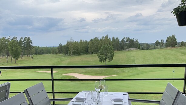 A table set for four on an outdoor deck with a view of a golf course. - Stuga på Nässjö Golfklubb (Nassjo)