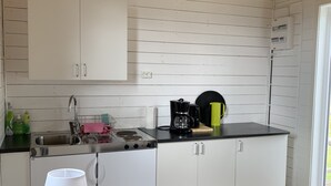 A modern kitchen with white cabinets, a stainless steel sink, and a coffee maker. - Stuga på Nässjö Golfklubb (Nassjo)