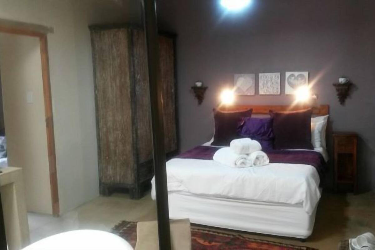 A bedroom with a bed, a wooden wardrobe, and wall-mounted lights.