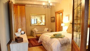 Une chambre confortable avec un lit, une chaise, une petite table sur laquelle se trouve un panier, un miroir et une porte en bois.