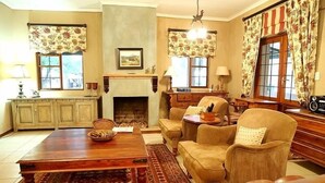 Un salon traditionnel avec une cheminée, des meubles en bois et des rideaux à motifs.