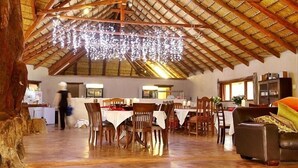 L’intérieur se caractérise par de hauts plafonds, des poutres en bois et un lustre. Des tables et des chaises sont disposées pour les repas.