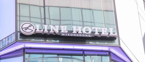 Exterior del Line Hotel en Meongdong, con fachada moderna de vidrio y señalización iluminada.