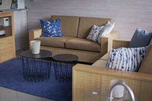 Ein gemütlicher Wohnbereich mit einer Couch, zwei kleinen Tischen und einem blauen Teppich.