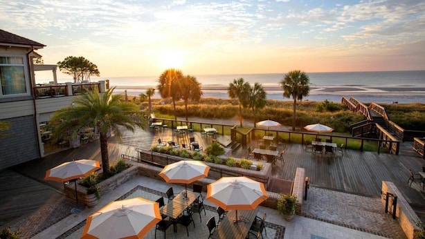 Terraza en la azotea con mobiliario exterior y vista a la playa al atardecer.