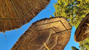 Une structure en forme de parasol à toiture de chaume, dotée d’un motif géométrique, qui fait probablement partie de l’architecture d’un bâtiment.