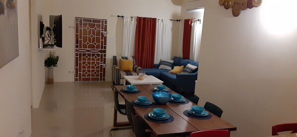 A dining area with a wooden table set for four, blue bowls, and a blue sofa with cushions in the background.