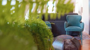 Ein modernes Wohnzimmer mit einem blauen Sessel, einem grauen Sofa und einem dekorativen Teppich.
