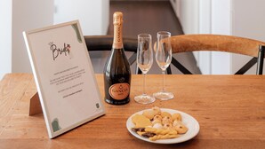 Ein Tisch mit einer Champagnerflasche, zwei Gläsern und einer Platte mit Snacks in einem modernen Hotelambiente.