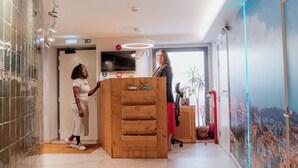 Eine Hotelhalle mit einer Rezeption, einem großen Wandgemälde und einem gefliesten Boden.