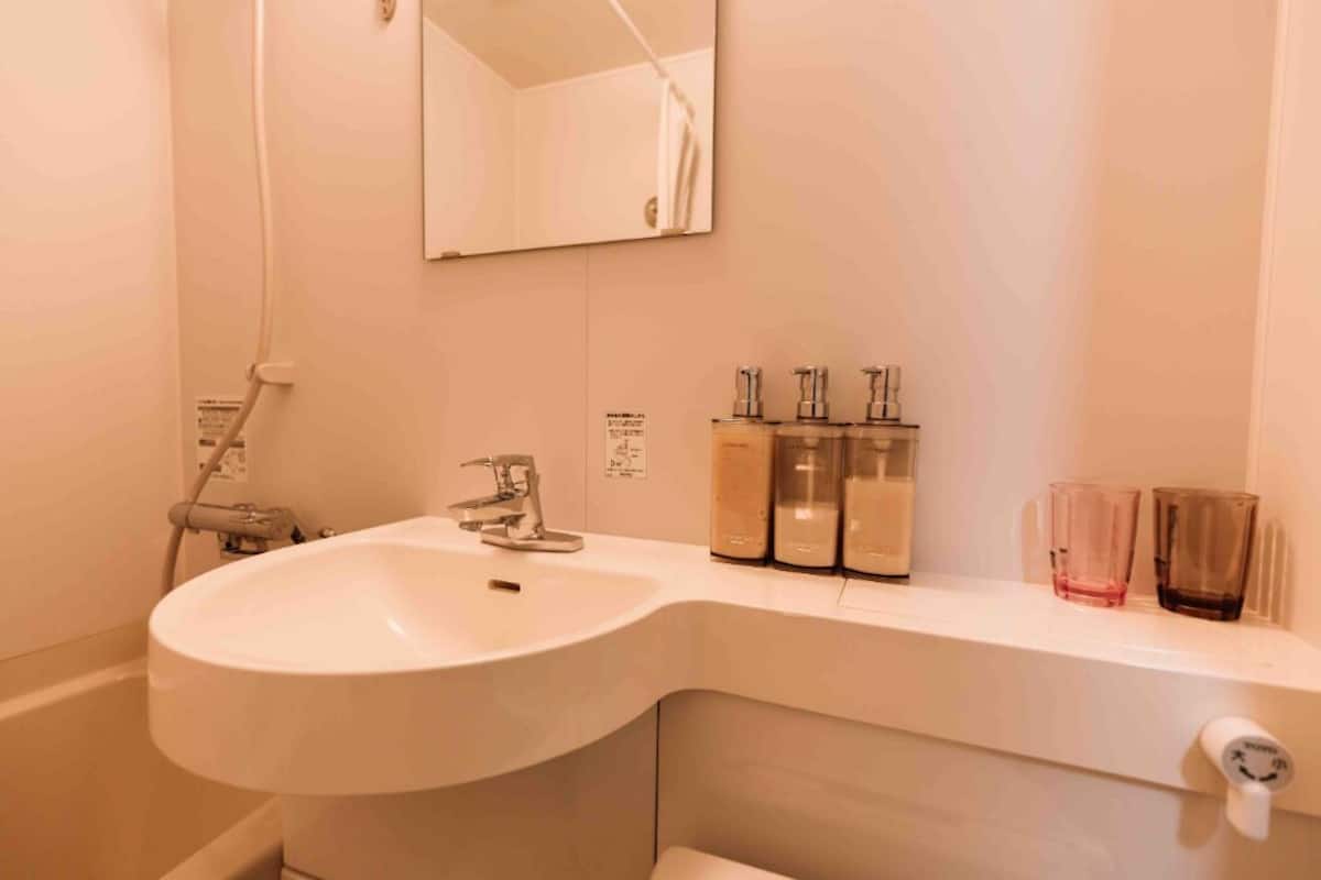 A bathroom with a white sink, a mirror, and a shelf with toiletries.