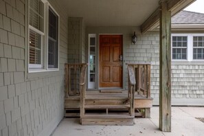 Una casa con un portico, una porta in legno e una finestra.