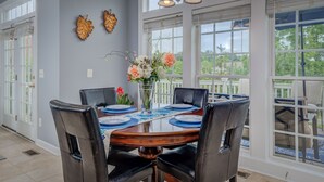 Comedor con una mesa redonda dispuesta para cuatro personas, rodeado de sillas de cuero negro.
