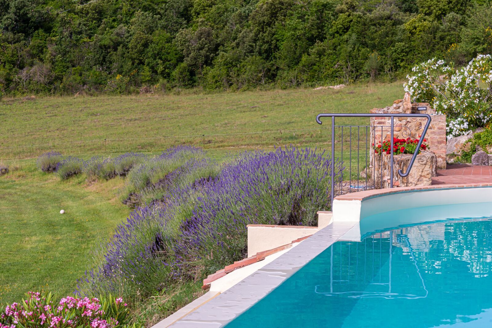 Una piscina con un muro de piedra y una barandilla de metal.