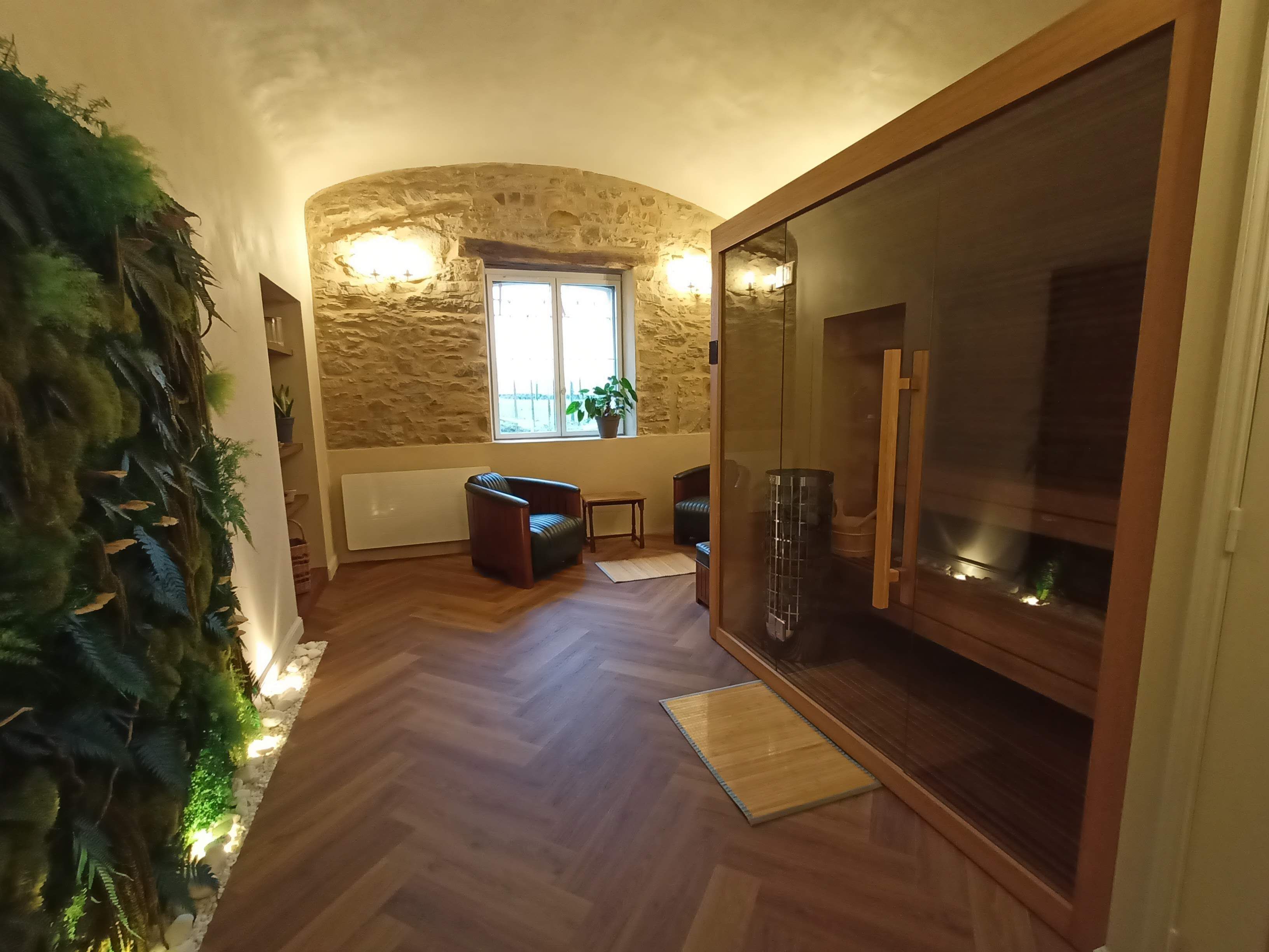 Quarto com parede de pedra, janela com vista, porta de correr de vidro e chão de madeira.