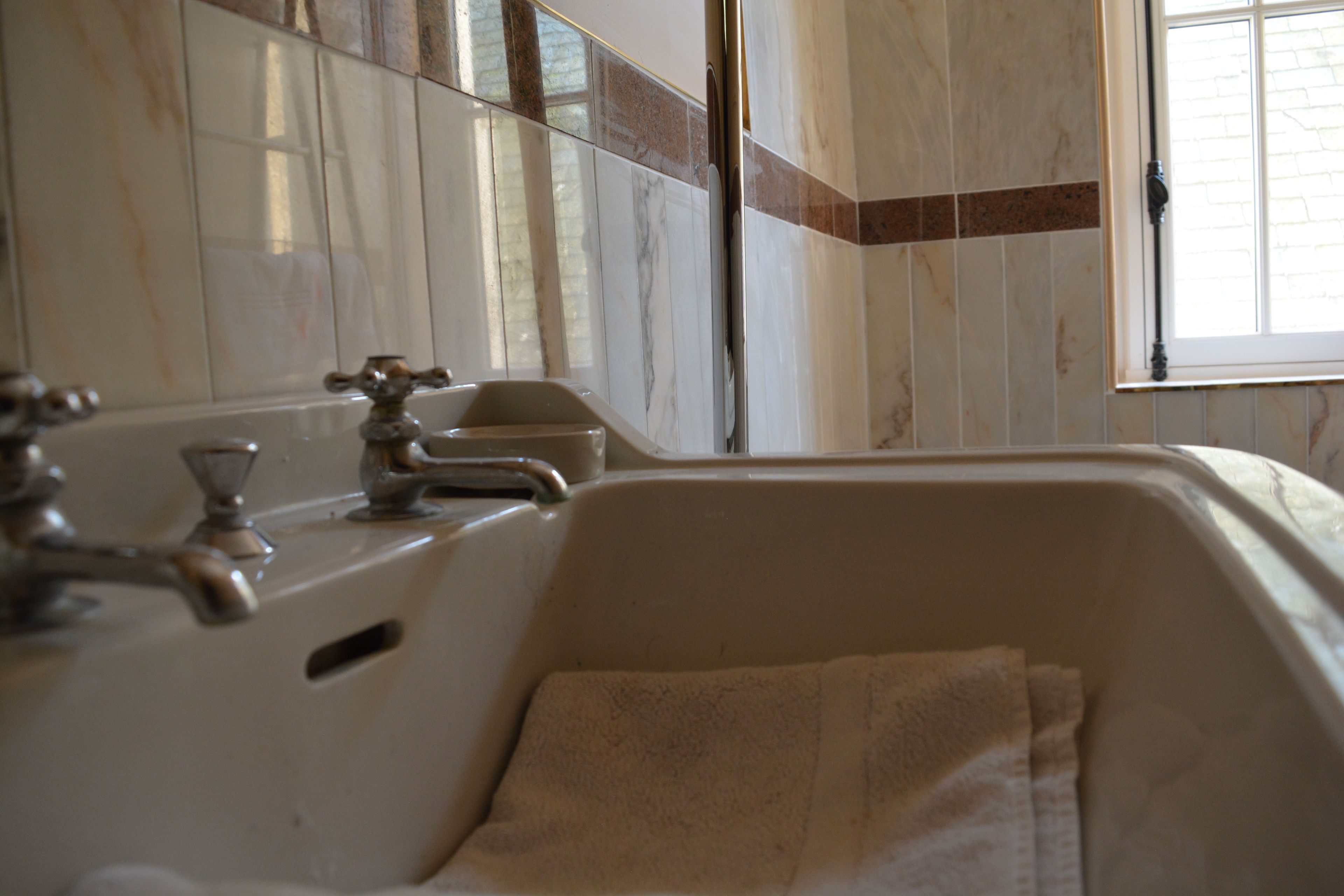 A bathroom with a bathtub, a towel, and a window.