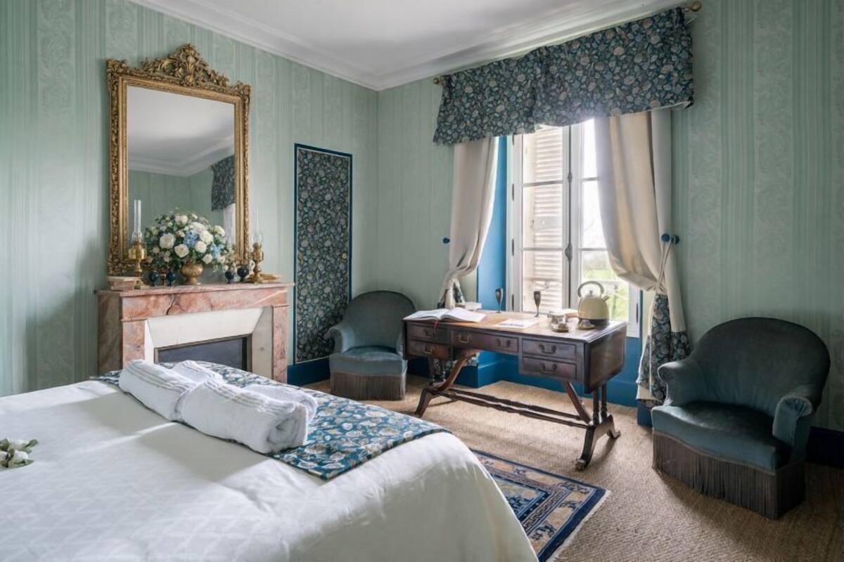 Ein Schlafzimmer mit Bett, Schminktisch, Stuhl und einem großen Spiegel.