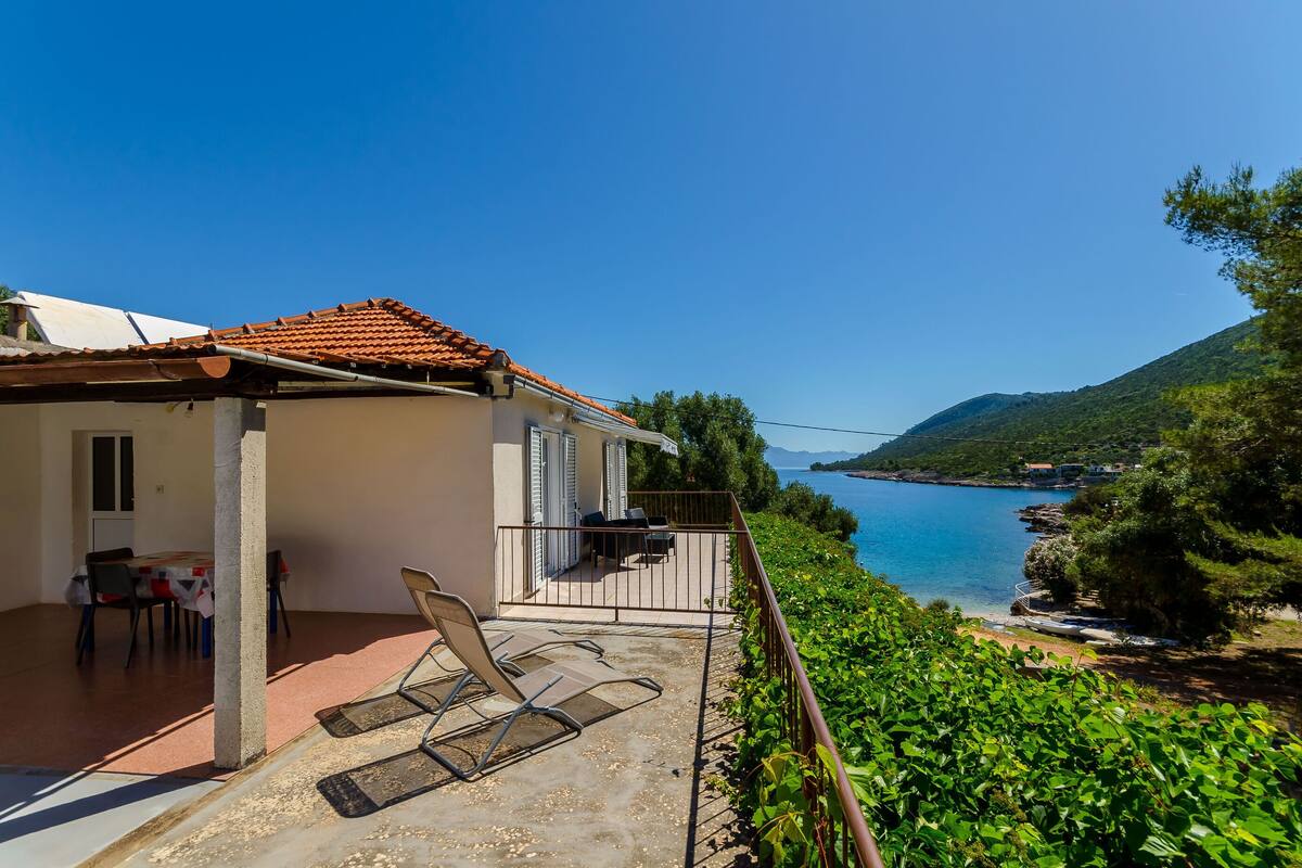 A villa with a terrace, outdoor seating, and a view of the sea.