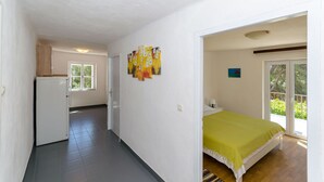 A room with a bed, a small kitchenette, a window, and a door leading to a balcony. - Apartments Nedeljko (Gdinj)